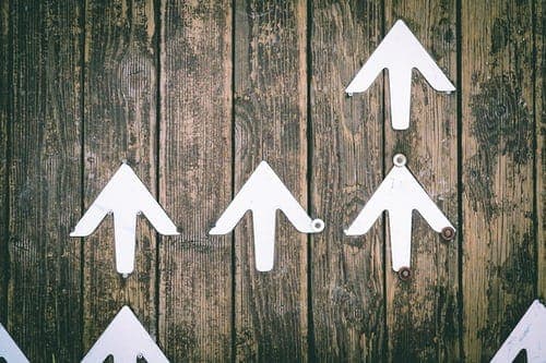White paper arrows on weathered wooden boards, all pointing upwards.