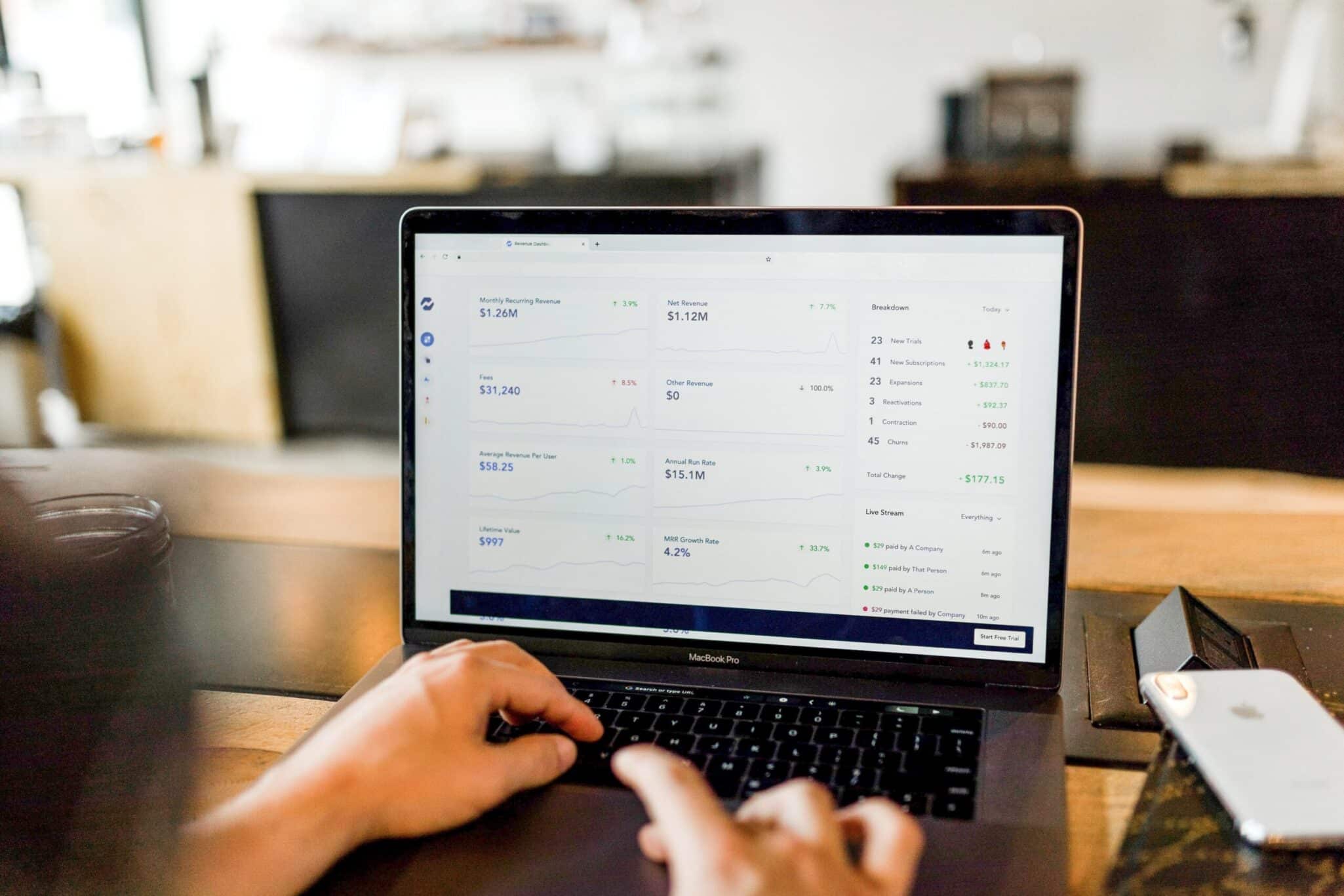 A person working at a laptop showing rows of records in an admin dashboard.