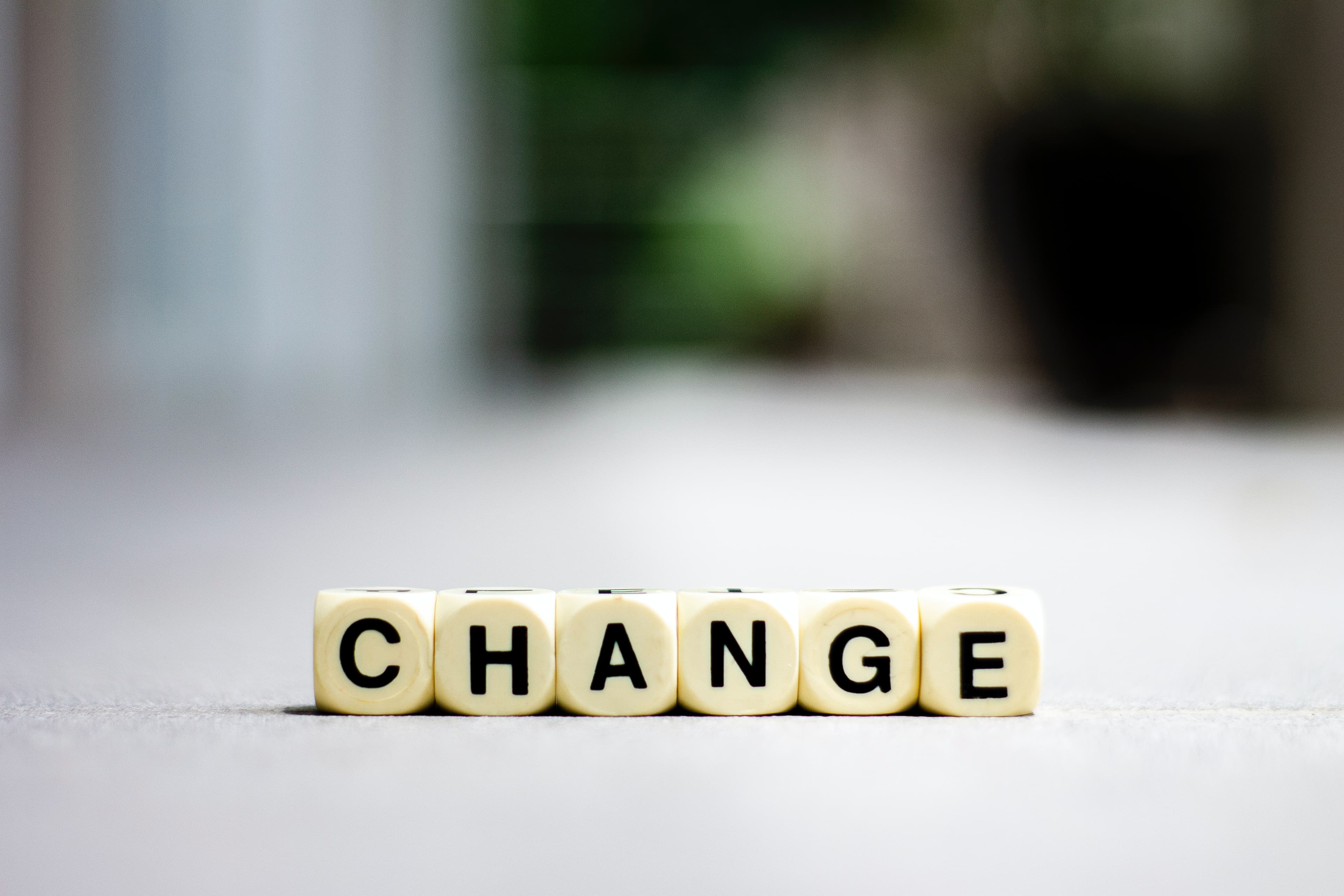 Lettered dice on a white surface spelling the word CHANGE.