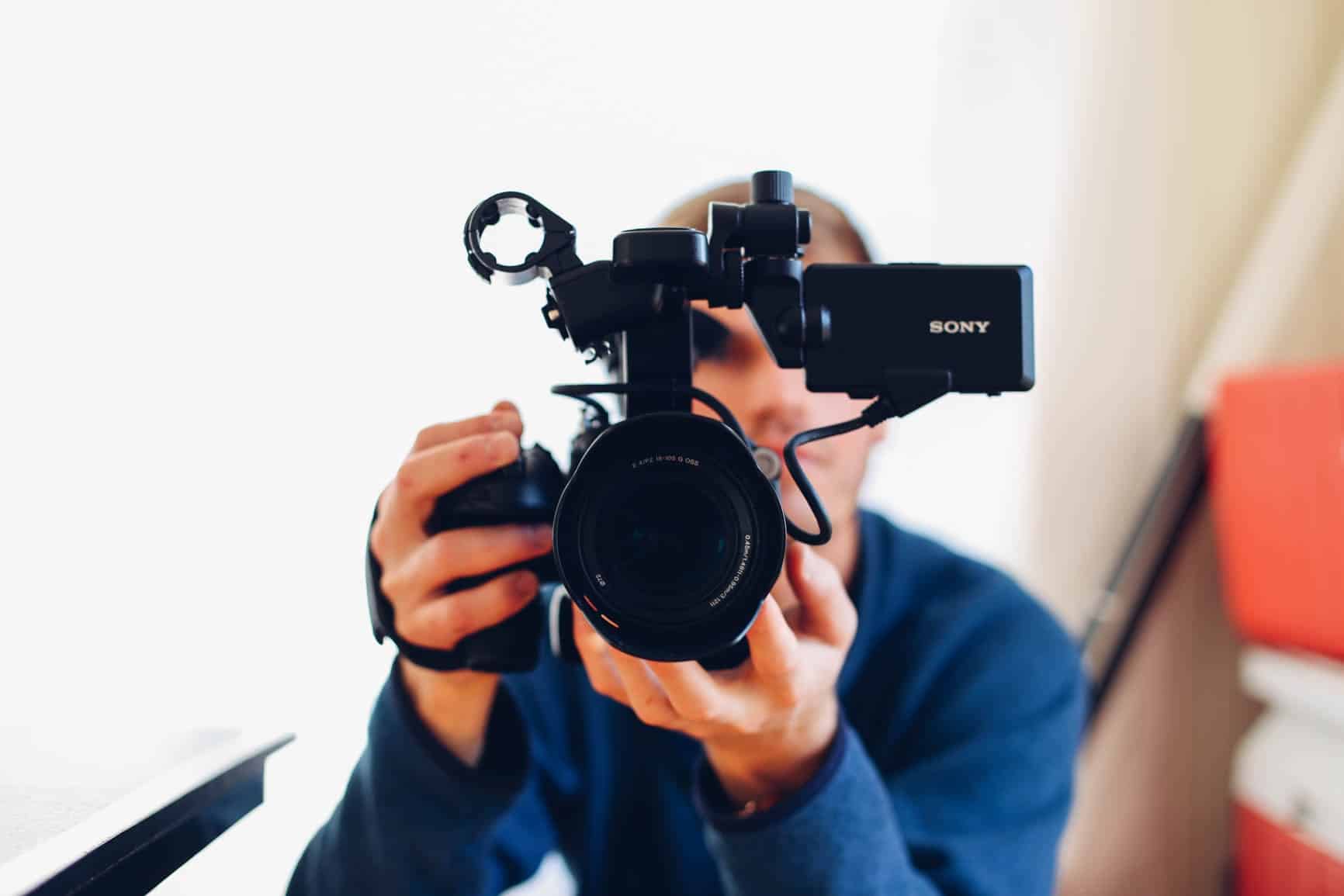 A person holding a professional video camera up to their eye.