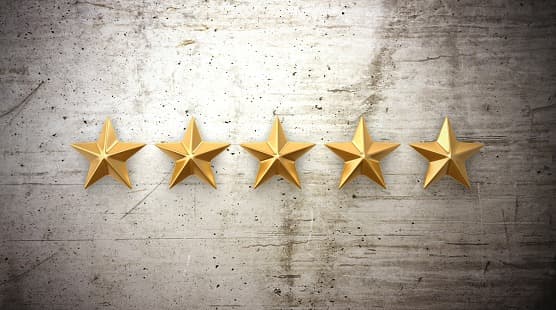 Five gold stars in a row on a concrete wall, representing a five star rating.