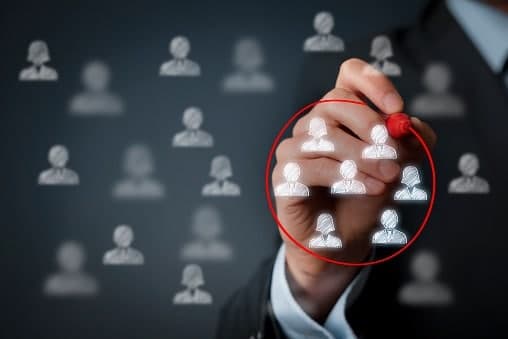 A person circling one customer icon among many with a red marker, representing audience targeting.