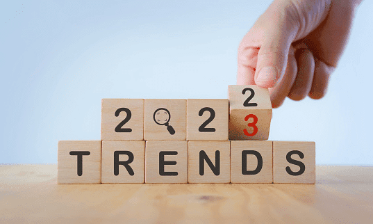 Wooden blocks spelling 2022 Trends, with a hand turning the last block to change it to 2023.