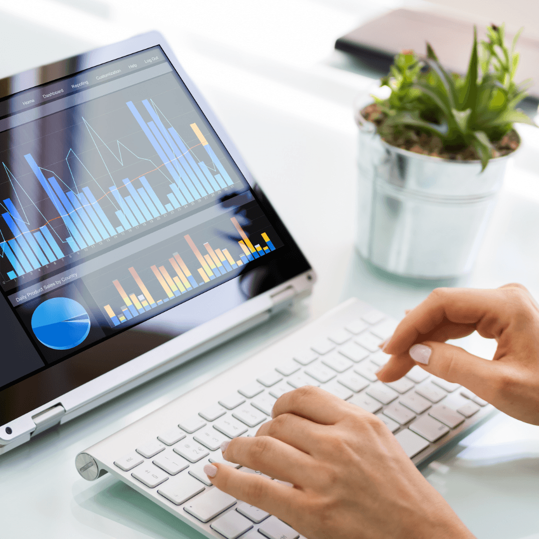 A person typing at a keyboard beside a tablet showing colourful analytics charts.