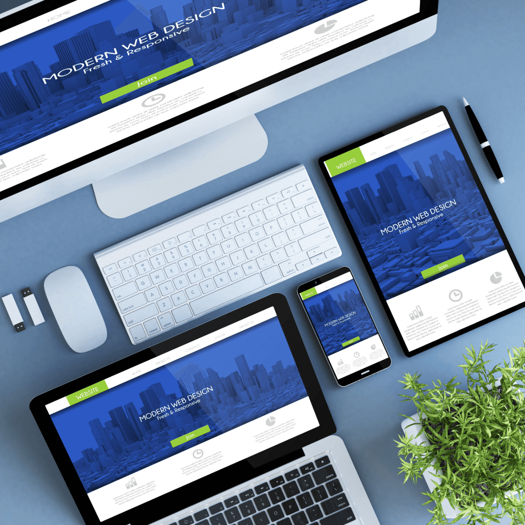 The same responsive website design shown across a monitor, tablet, phone and laptop on a blue desk.