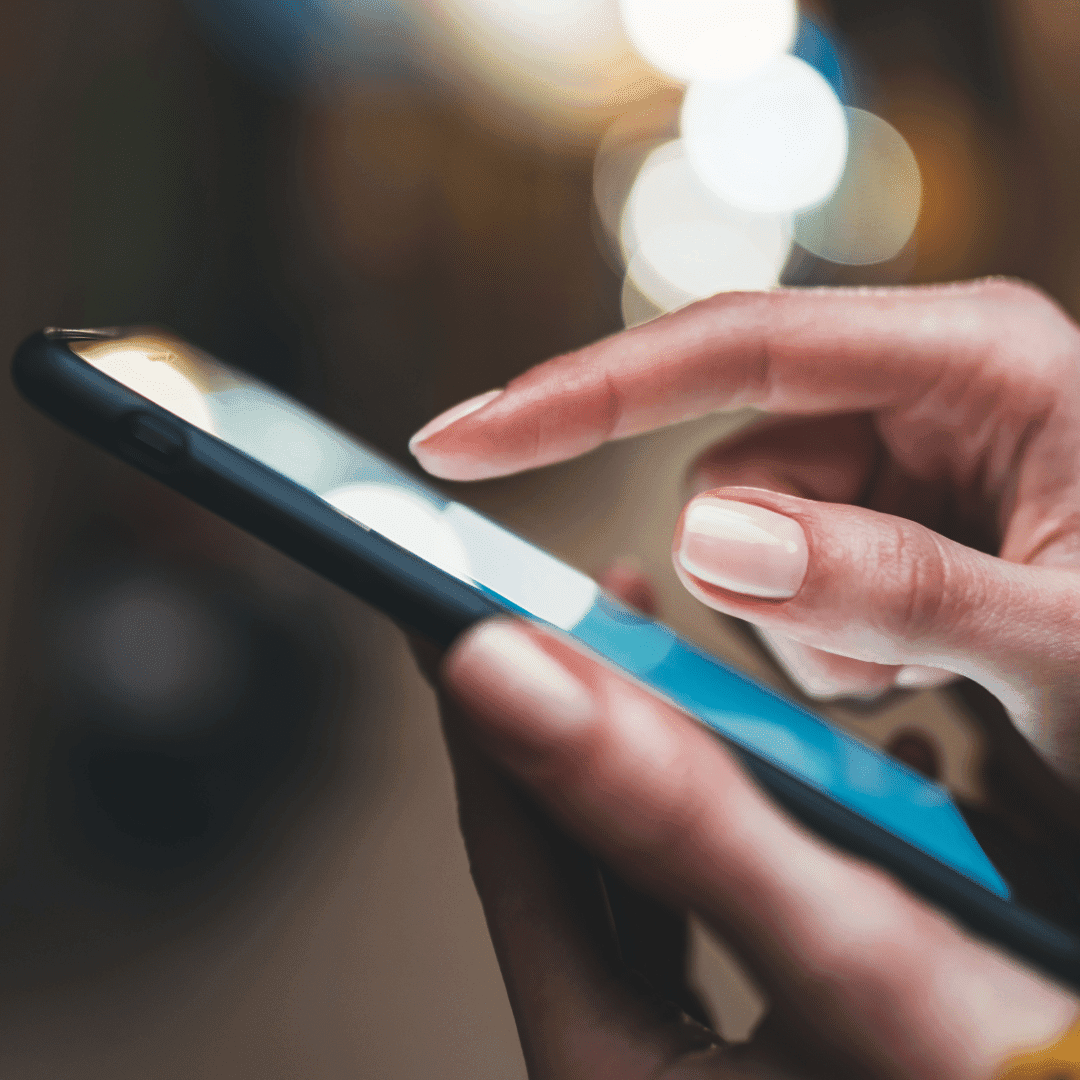 A finger tapping the screen of a smartphone, with bokeh lights in the background.