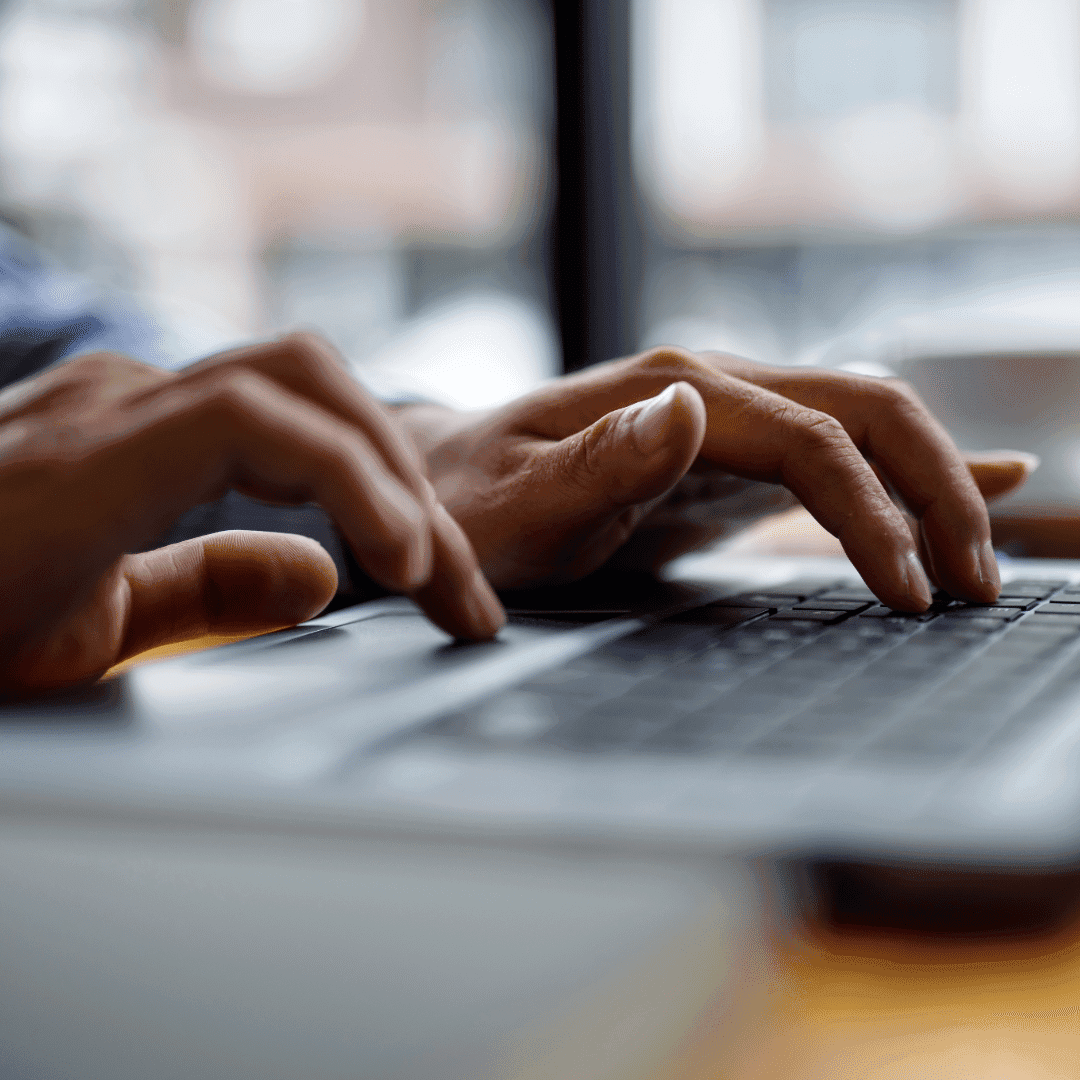 Close-up of hands typing on a laptop keyboard.