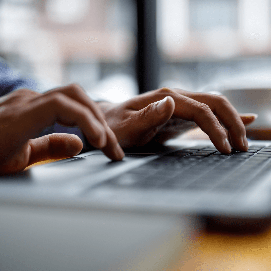 A web developer at a desk comparing code on a large monitor against printed page layouts.