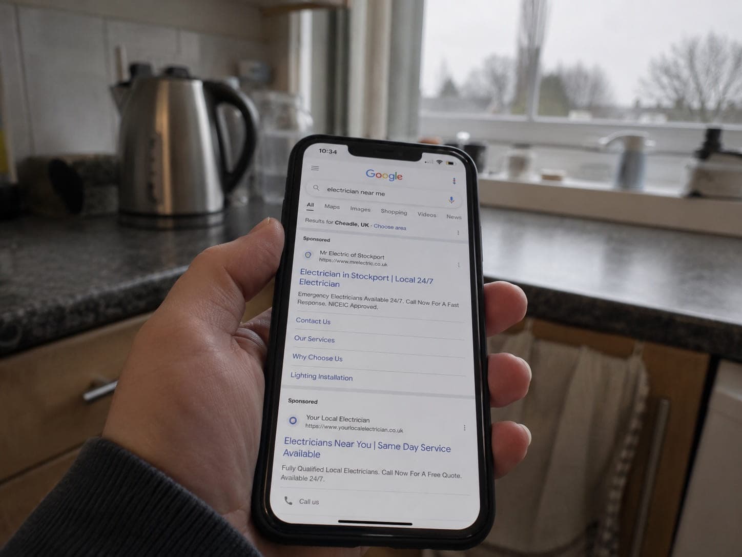 Someone searching for a local tradesperson on their phone in a kitchen