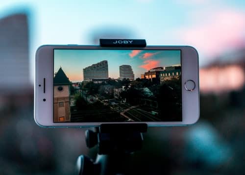 A phone mounted on a tripod filming a city skyline at sunset.