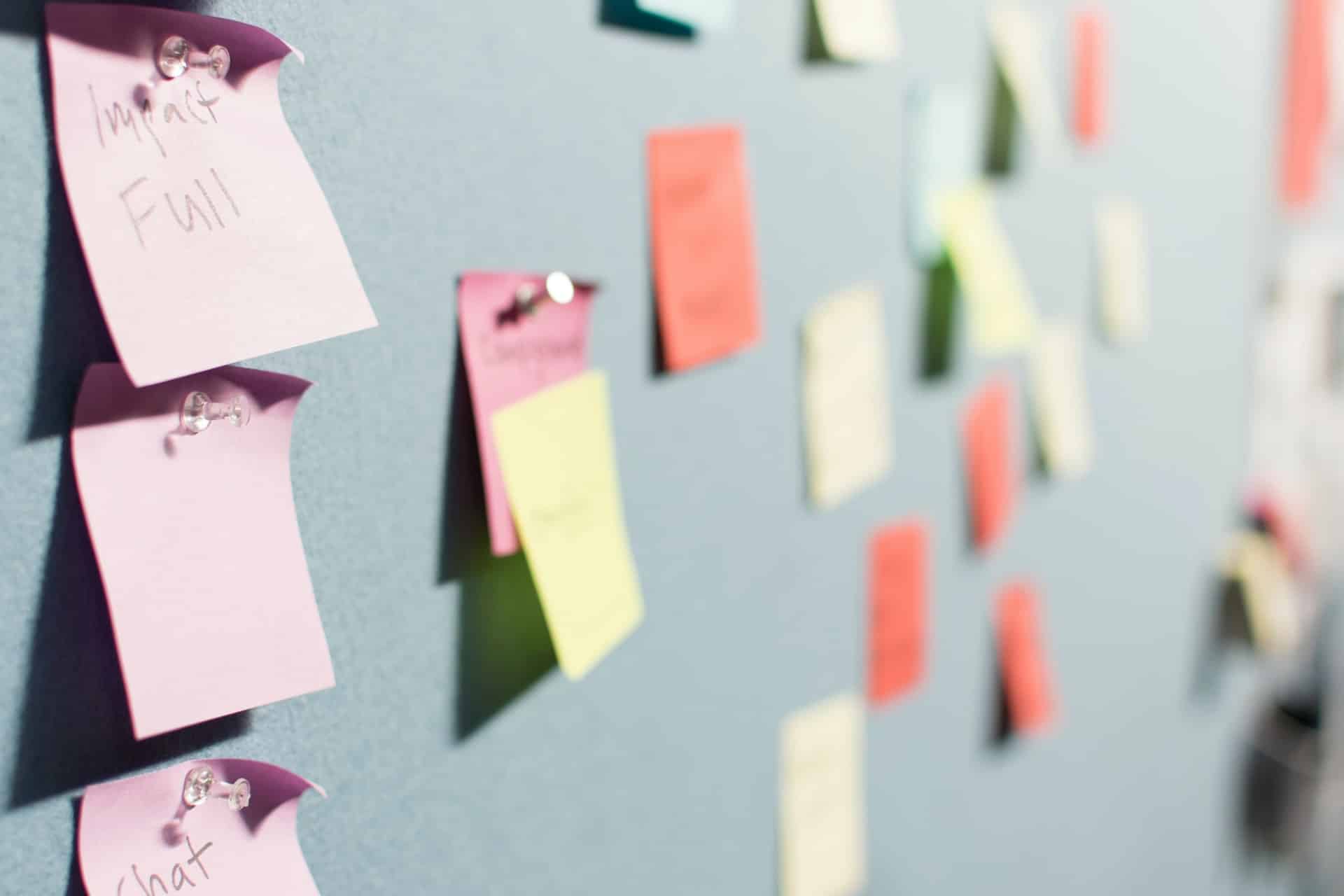 Coloured sticky notes pinned in rows across a grey noticeboard.