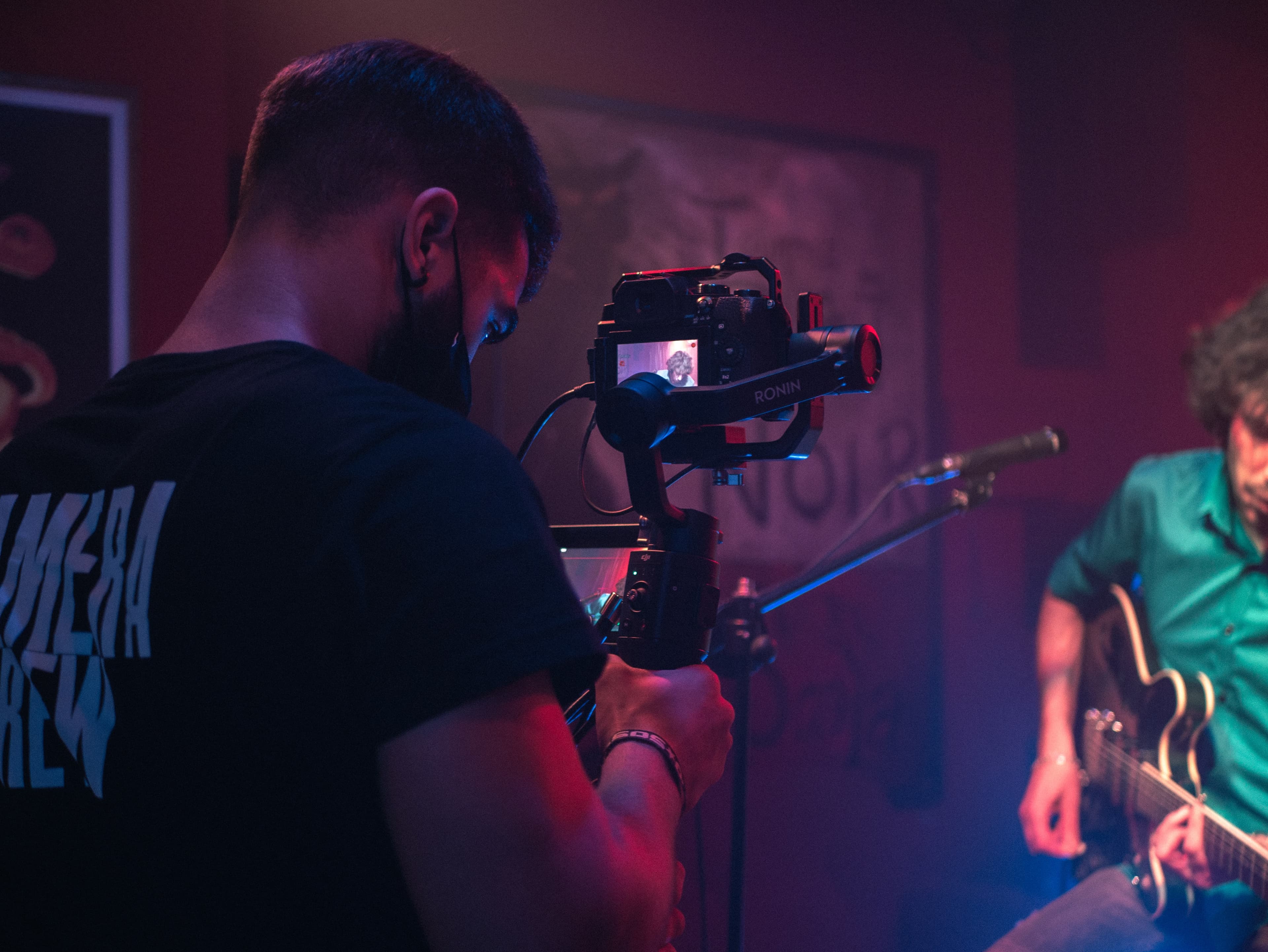 A camera operator filming a guitarist performing in a small venue.