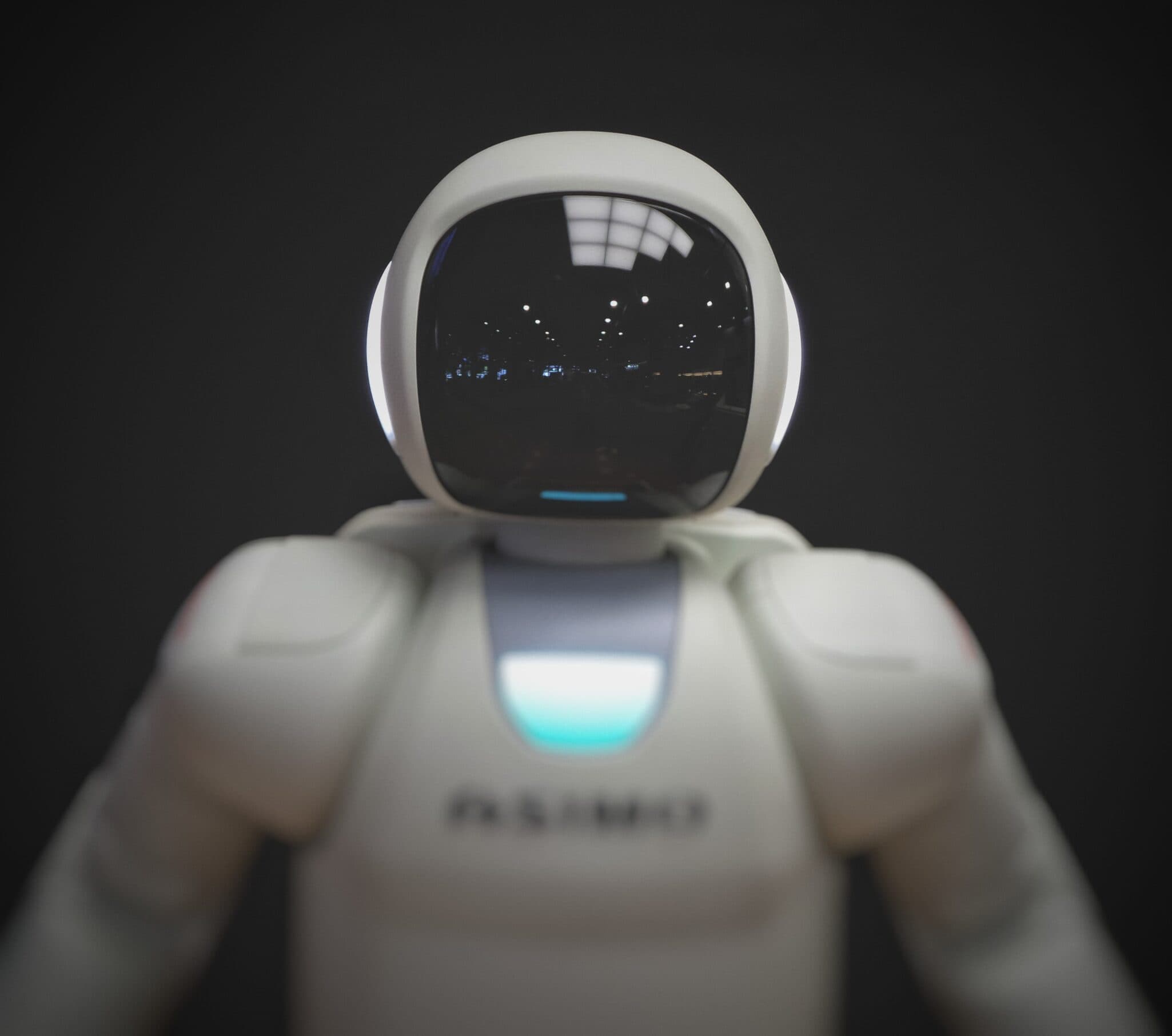 A white humanoid Asimo robot photographed against a dark background.
